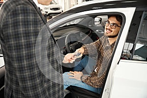 Man new car owner taking key from salesman for test drive choosing automobile