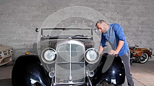 A man next to a classic car in a garage with automotive design