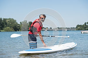 Man next to stand-up paddle board on lake