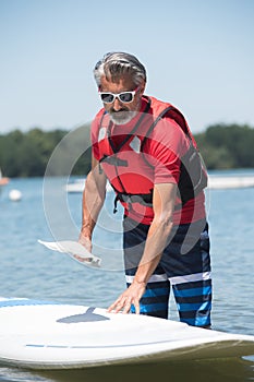 Man next to stand-up paddle board on lake