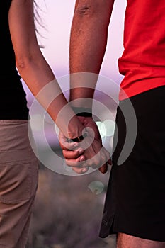 A man next to a woman, guy and a girl are standing close, touching each other, holding hands. The concept of first teenage love.