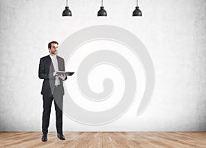 Man with notebook in hands on grey background, mockup empty wall