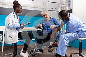 Man nurse checking injured knee leg of sick retired senior patient