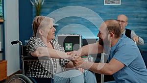 Man nurse holding hands and comforting pensioner with disability