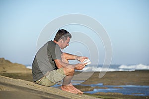 Man by Oceand reading and listenting to music