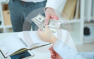 Man offering batch of hundred dollar bills.