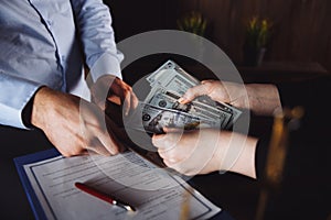 Man offering batch of hundred dollar bills. Hands close up. Venality, bribe, corruption concept. Hand giving money -