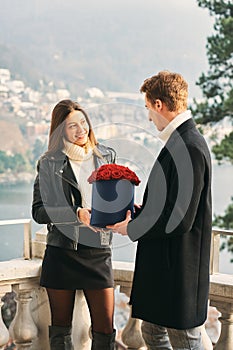 Man offering flower box of red roses to beautiful young woman