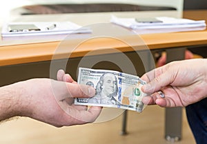 Man offering of hundred dollar bill. Hands close up. Corruption concept.