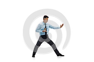 Man in office clothes practicing taekwondo on white background. Unusual look for businessman in motion, action. Sport