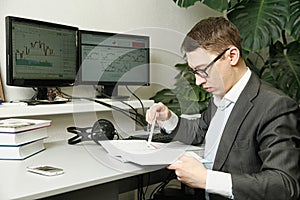 The man in the office for computer monitors studies records in a notebook