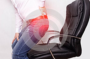 A man in the office holding his back from a chair, the concept of back pain, intervertebral hernia and osteochondrosis
