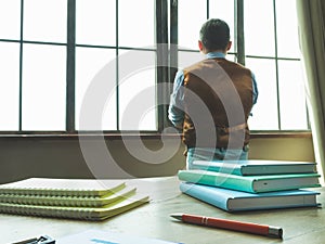 Man in the office looks out the window. The businessman is pondering.