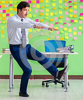 Man in the office with many conflicting priorities doing exercis