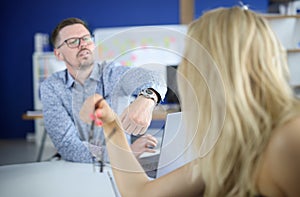 Man in an office points to watch to his employee.