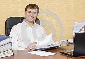 The man in the office smiling scans documents