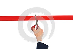 Man in office suit cutting red ribbon isolated on white