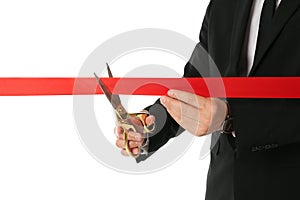 Man in office suit cutting red ribbon isolated on white