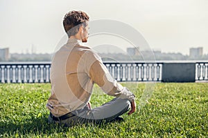 Man in office suit meditate on the green lawn