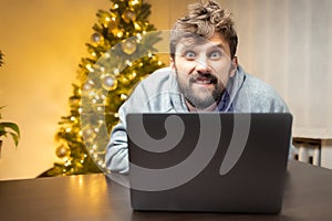 A man in the office, tired from work and shaggy, sits in front of a laptop and works