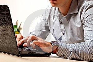 A man in the office typing on a laptop keyboard. Businessman at work