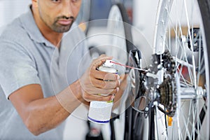 man oiling bicycle chain and gear with oil spray