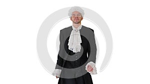 Man in old-fashioned laced frock coat and white wig walking in a mannered way looking at camera on white background.