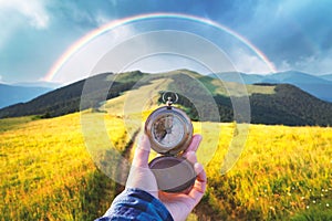 Man with old metal compass in hand on mountains road