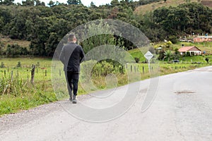 Man on an old road to a village with a beautiful green meadow.