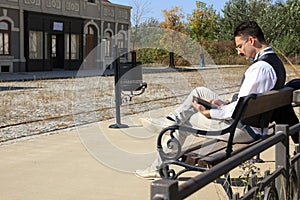 Man in old town relaxing sitting on bench reading book