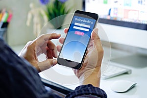 Man with online bank application phone at desk workspace in office