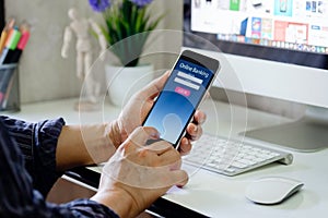 Man with online bank application phone at desk workspace in office.