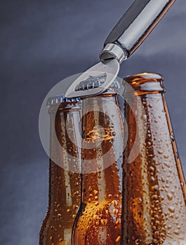 Man open fresh cold beer ale bottles with drops and stopper open with bottle opener