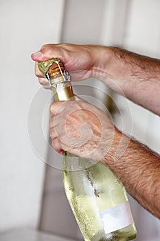 Man is opening a bottle of champagne. Waiter opens a bottle of wine. Man hands open bottle of champagne alcohol and wine drink.