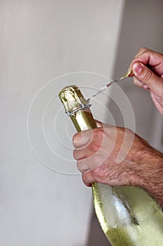 Man is opening a bottle of champagne. Waiter opens a bottle of wine. Man hands open bottle of champagne alcohol and wine drink.