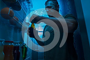 Man opening a bottle of cold beer from the fridge