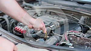 Man opening car hood and checking oil level car engine outdoors. Hands of a man close up.