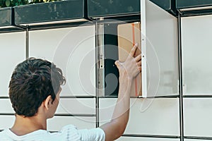 Man opening a door of post office box on the city street and receive a parcel. Man carrying box from post office delivery.