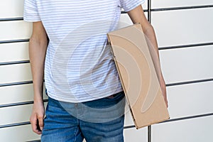 Man opening a door of post office box on the city street and receive a parcel. Man carrying box from post office delivery.