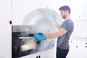 Man Opening Oven Filled With Smoke