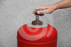 Man opening red gas cylinder near wall, closeup