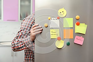 Man opening refrigerator door with paper sheets