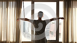 Man Opening in Slow Motion the Window Curtain on a Sunny Morning in a Hotel Room, a Man Looking on the Window Relaxed