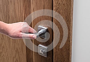 The man opens the door. Close - up of hand and door handle, white wall