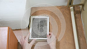 Man opens a dusty ventilation grill to clean the ventilation
