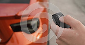 Man opens his car using control remote key pressing button, hand closeup.