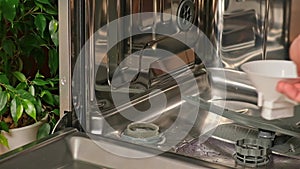 man opens salt compartment of dishwasher, pours salt into through funnel. Softening hardness water