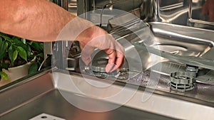 man opens salt compartment of dishwasher, pours salt into through funnel. Softening hardness water