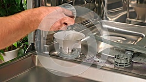 man opens salt compartment of dishwasher, pours salt into through funnel. Softening hardness water