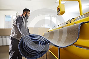 Man operating carpet automatic cleaning machine in professional laundry service